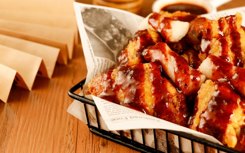 Close-up of sauced wings being plated by a chef